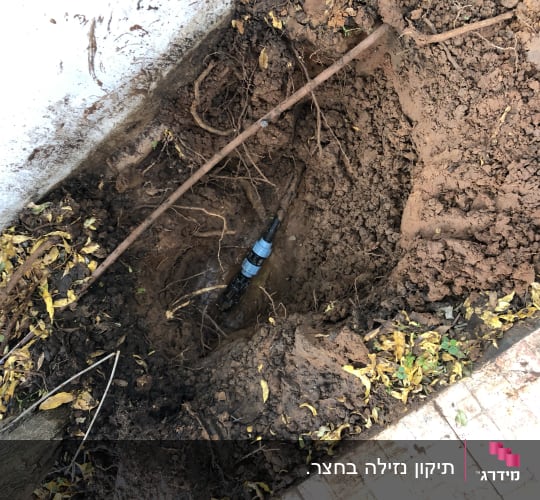 צינור מים חשוף באדמה עם חיבור פלסטיק